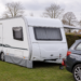 Witte toercaravan naast een auto op een Nederlandse camping of stalling, in een rustige situatie die past bij caravanverzekering.
