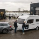 Caravan wordt ingeladen bij een drukke Nederlandse caravanstalling met meerdere caravans op de achtergrond.