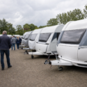 Meerdere caravans staan dicht op elkaar op een Nederlands caravanterrein terwijl bezoekers rondkijken.