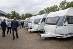Meerdere caravans staan dicht op elkaar op een Nederlands caravanterrein terwijl bezoekers rondkijken.