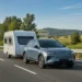 Elektrische SUV trekt een caravan op de snelweg door groen landschap