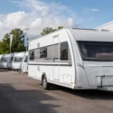 Nieuwe caravans op een dealerterrein bij een werkplaats, passend bij de stijgende verkoop van caravans en de aandacht voor stalling, onderhoud en verzekering.