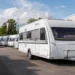 Nieuwe caravans op een dealerterrein bij een werkplaats, passend bij de stijgende verkoop van caravans en de aandacht voor stalling, onderhoud en verzekering.